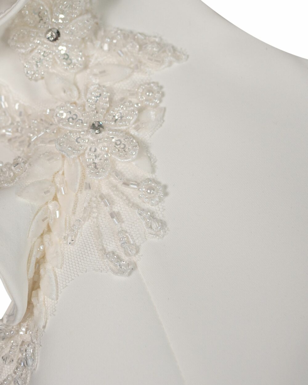 Detail van een communiejurk in wit