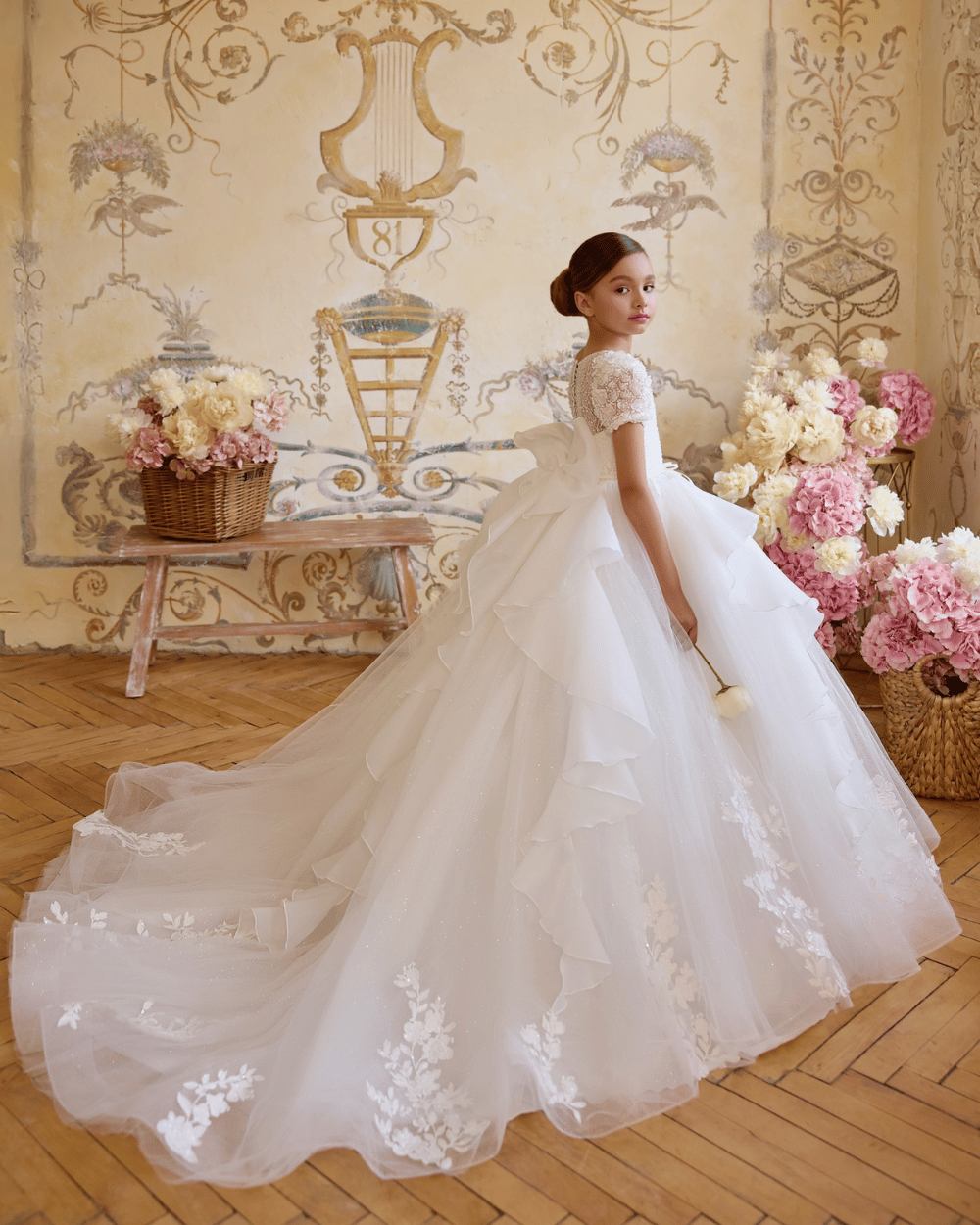 Meisje in luxe communiejurk met korte pofmouwtjes, kanten lijfje en subtiele glittertule rok, ideaal voor communie.