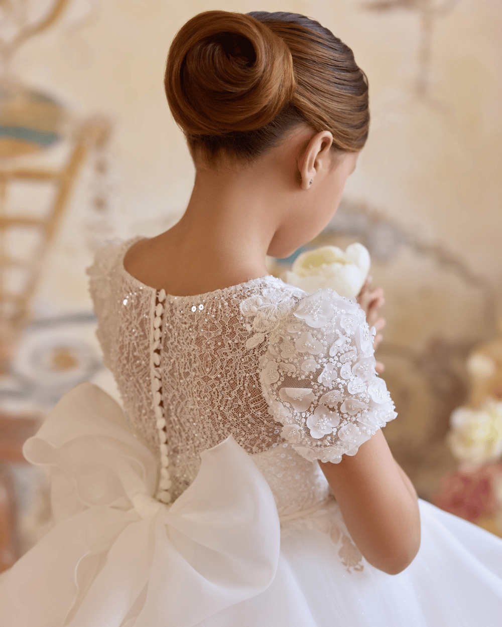 Detailfoto van luxe communiejurk met kanten lijfje en parelknopen, perfect voor eerste communie of bruidsmeisje.