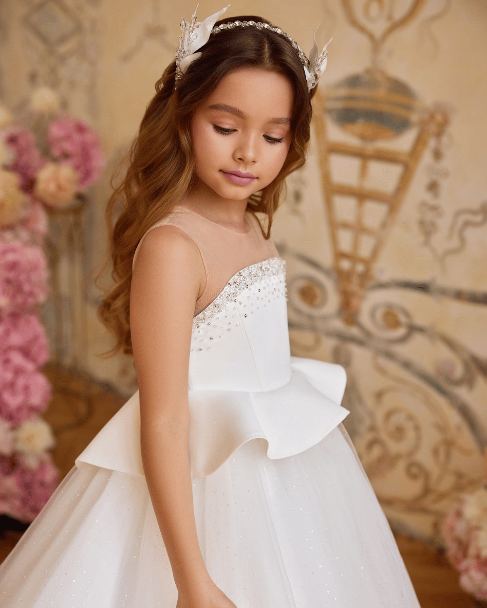 Ivoren communiejurk met moderne peplum en subtiele pareldetails op het lijfje, gecombineerd met een lange tule rok.